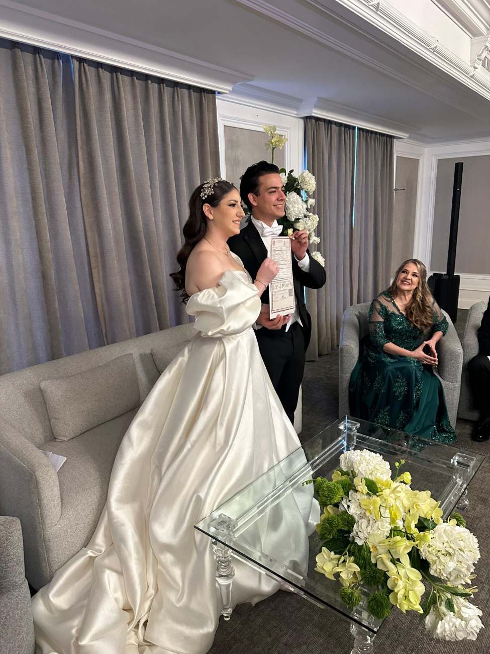 Novios con su acta de matrimonio en una suite de hotel
